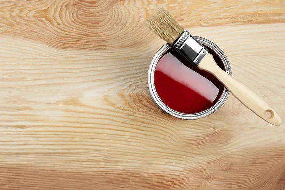 Ein kleiner Eimer mit Holzschutz und ein Pinsel auf Holz